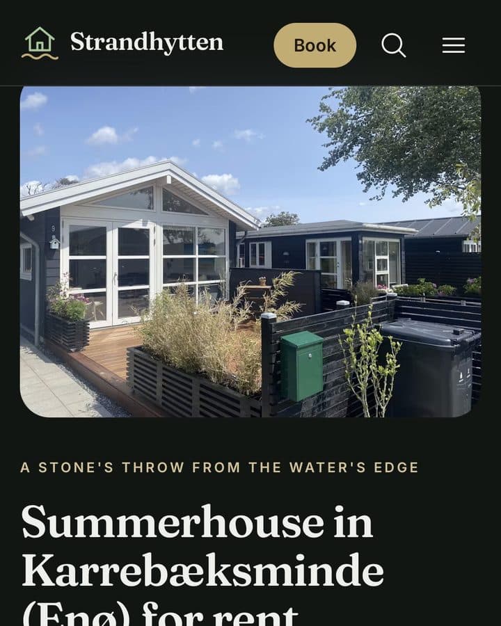 Mobile view of the Strandhytten website: the black summerhouse with its terrace, and the heading Summerhouse in Karrebæksminde (Enø) for rent